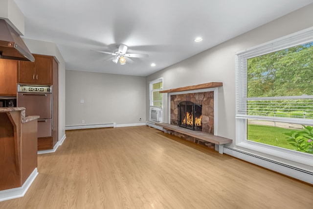 living room with a baseboard radiator, a stone fireplace, ceiling fan, and light hardwood / wood-style floors