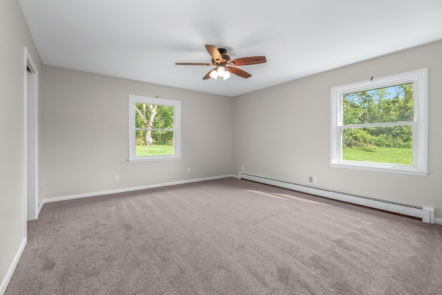 carpeted spare room with ceiling fan, a baseboard heating unit, and a healthy amount of sunlight