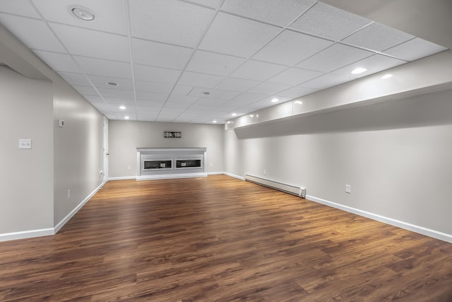 unfurnished living room featuring a baseboard radiator, a drop ceiling, and hardwood / wood-style floors