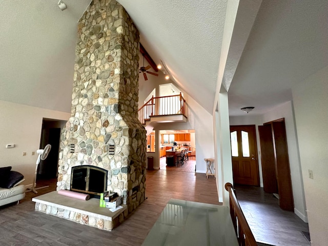 living room featuring a textured ceiling, a fireplace, high vaulted ceiling, and wood-type flooring