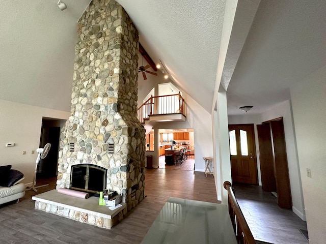 living room with a fireplace, a textured ceiling, baseboards, and wood finished floors