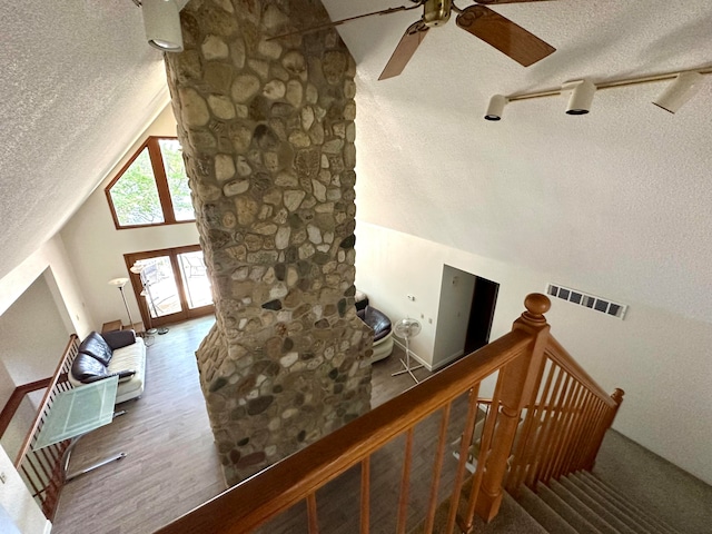 staircase featuring lofted ceiling, hardwood / wood-style floors, and a textured ceiling