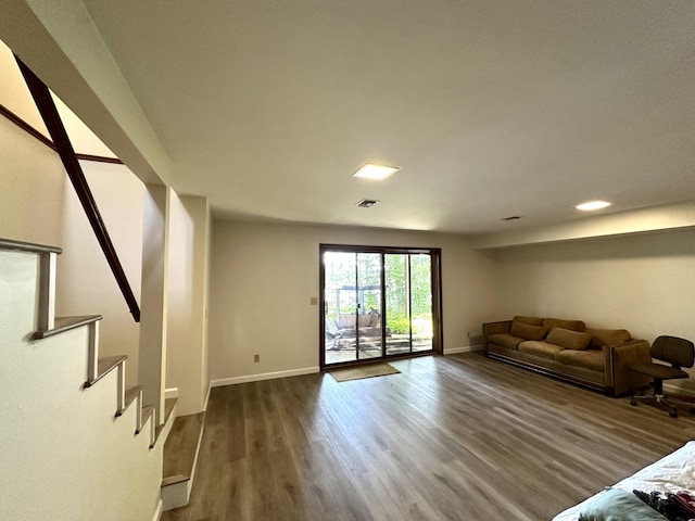 unfurnished living room featuring stairway, wood finished floors, and baseboards