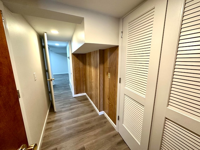 corridor with hardwood / wood-style flooring and wooden walls