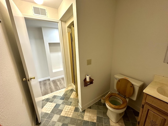 bathroom with vanity, baseboards, visible vents, a stall shower, and toilet