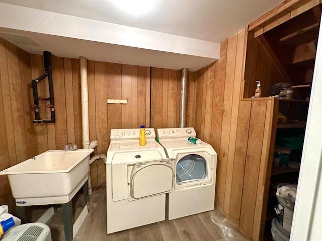 laundry area with separate washer and dryer, sink, light hardwood / wood-style flooring, and wood walls