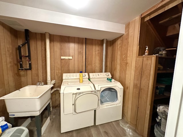 washroom with a sink, separate washer and dryer, wood finished floors, and wooden walls