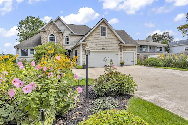 view of front facade featuring stone siding, roof with shingles, and concrete driveway