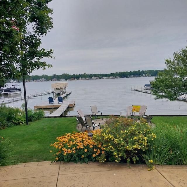 view of dock with boat lift, a lawn, and a water view