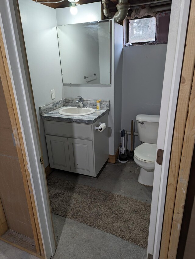 bathroom featuring concrete floors, toilet, and vanity