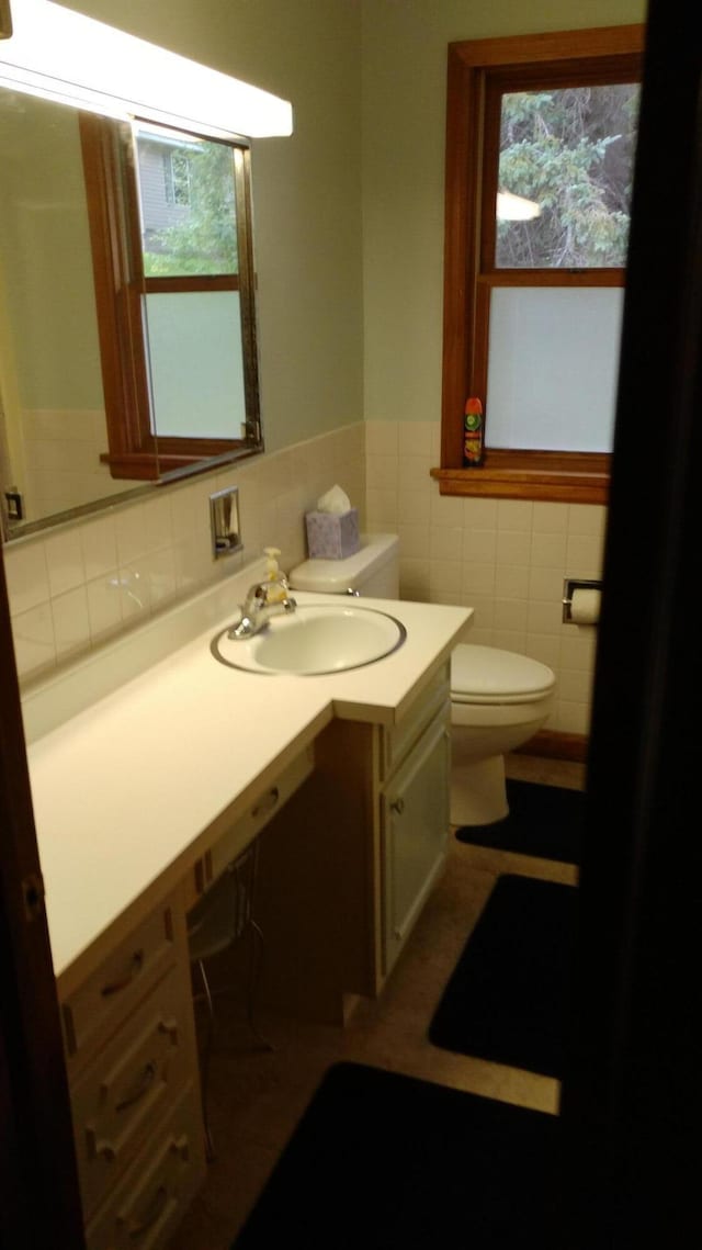 bathroom with vanity, decorative backsplash, tile walls, and toilet