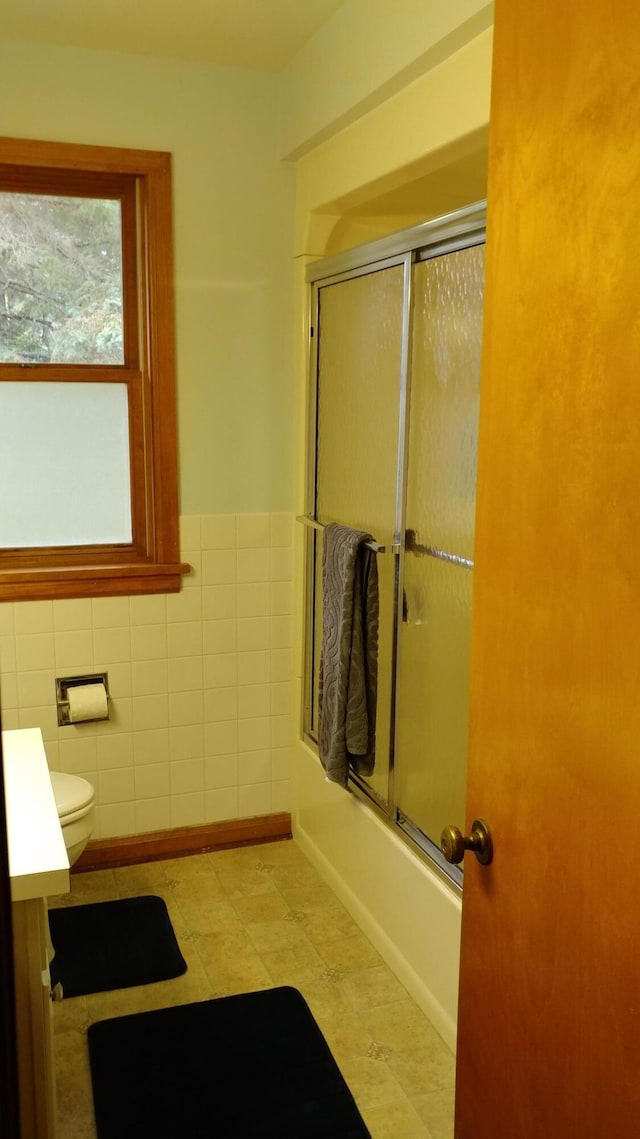 full bathroom with enclosed tub / shower combo, toilet, vanity, tile walls, and tile patterned floors