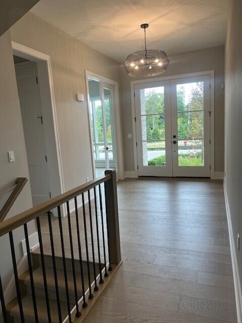 doorway with wood finished floors, stairway, french doors, and baseboards