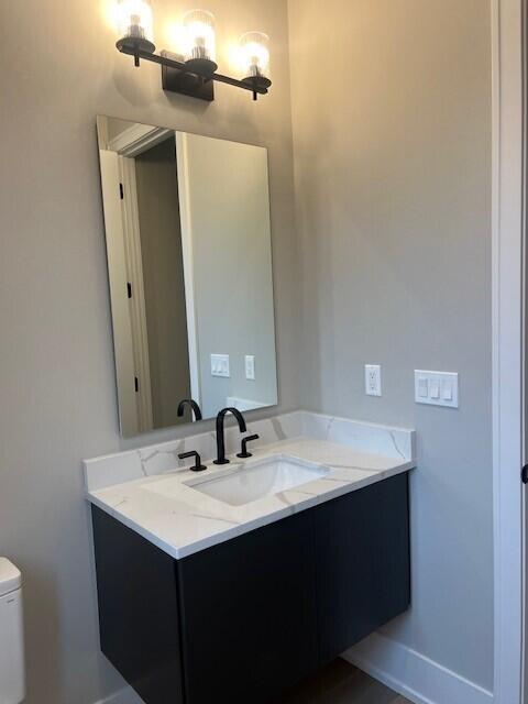 bathroom featuring toilet, vanity, and baseboards