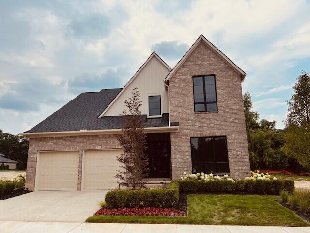 view of front facade with brick siding, concrete driveway, a garage, and a front yard