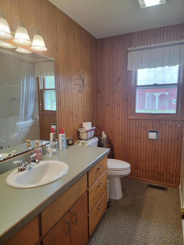 bathroom featuring vanity, toilet, and wooden walls