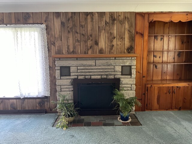 unfurnished living room with carpet floors, a stone fireplace, and wooden walls