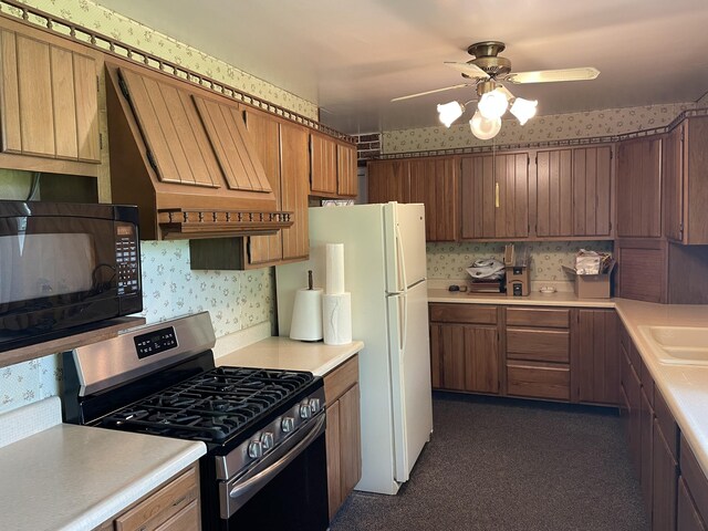 kitchen featuring white refrigerator, custom exhaust hood, stainless steel range with gas stovetop, and ceiling fan