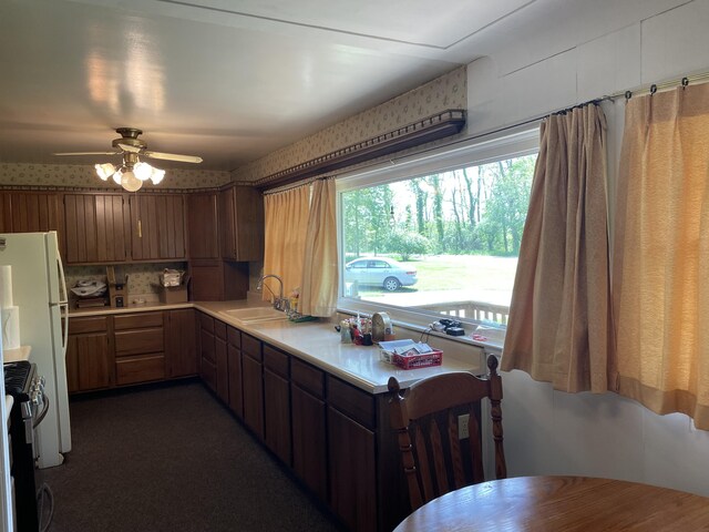 kitchen featuring dark carpet, tasteful backsplash, ceiling fan, stove, and sink