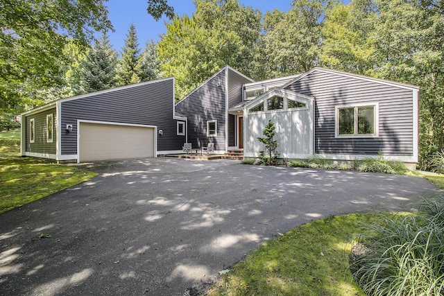 mid-century home featuring a front lawn, a garage, and driveway