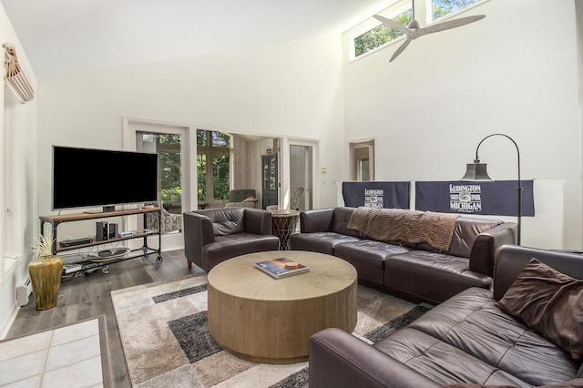 living room with a healthy amount of sunlight, a high ceiling, a ceiling fan, and wood finished floors