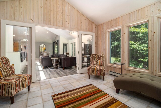 sitting room with wooden walls, a baseboard heating unit, light hardwood / wood-style floors, and high vaulted ceiling