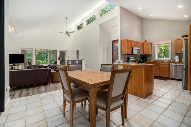 dining room with high vaulted ceiling, sink, light wood-type flooring, and ceiling fan