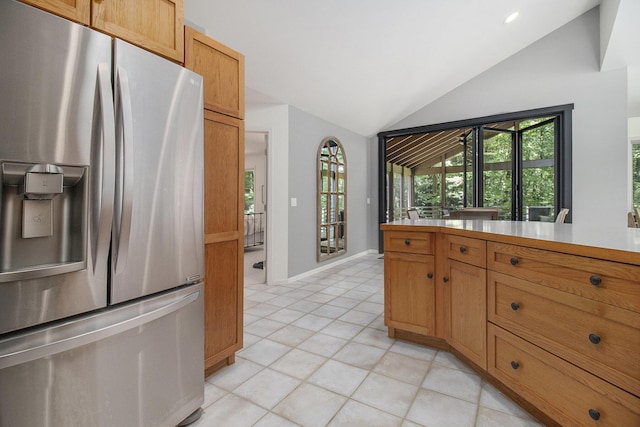 kitchen featuring a wealth of natural light, vaulted ceiling, light tile patterned floors, and stainless steel fridge with ice dispenser