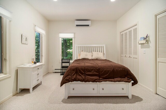 bedroom featuring a baseboard radiator, a wall unit AC, light carpet, and a closet