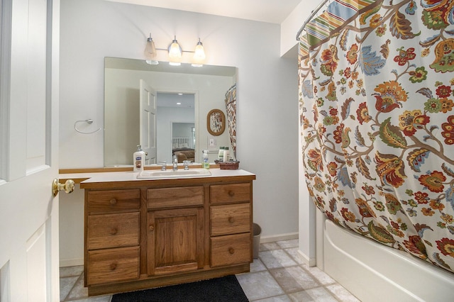 ensuite bathroom featuring connected bathroom, vanity, shower / bath combo with shower curtain, and baseboards