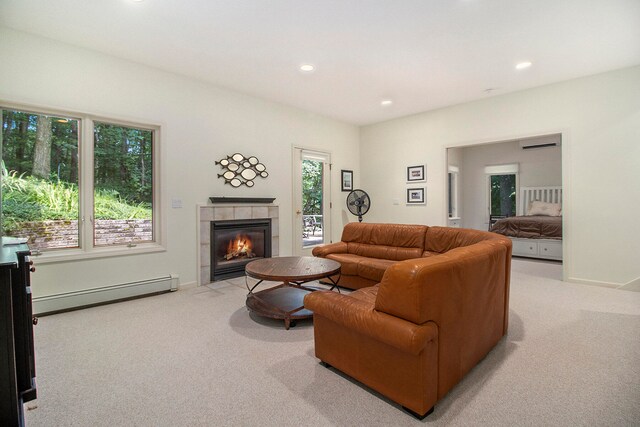 carpeted living room with a baseboard heating unit, a tile fireplace, and plenty of natural light