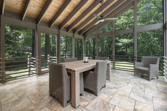 sunroom featuring a ceiling fan, vaulted ceiling with beams, wood ceiling, and a healthy amount of sunlight