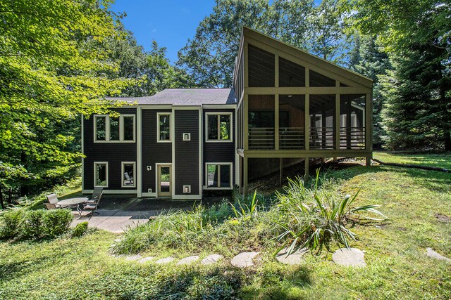 back of property with a patio area, a sunroom, and a yard