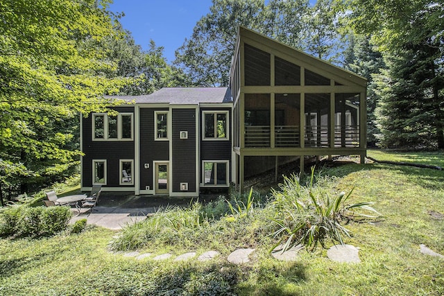 rear view of property featuring a yard, a sunroom, and a patio area