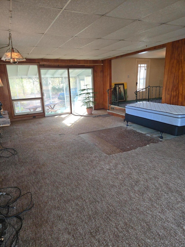 recreation room with carpet flooring, a paneled ceiling, and wooden walls