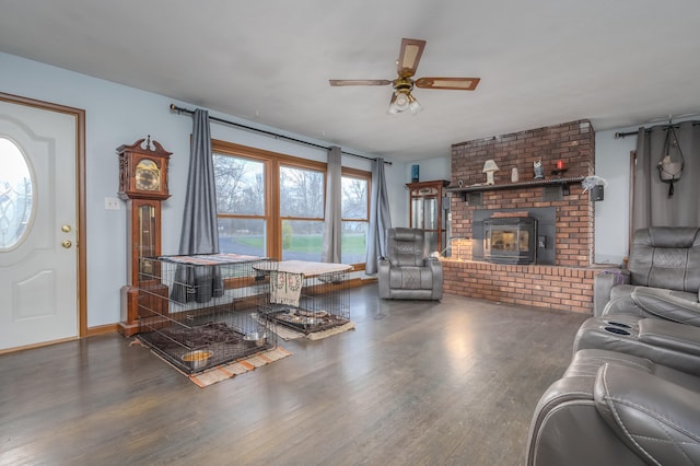 living room with ceiling fan, a wood stove, and dark wood-type flooring