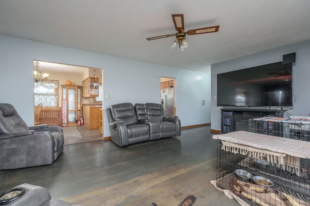 living room featuring ceiling fan with notable chandelier and dark wood-type flooring