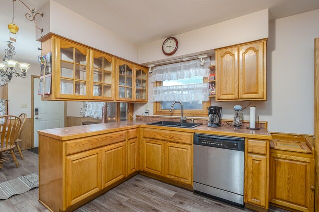 kitchen featuring kitchen peninsula, sink, stainless steel dishwasher, and light hardwood / wood-style floors