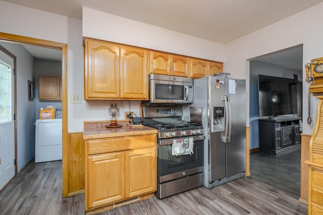 kitchen featuring hardwood / wood-style flooring, washer / dryer, stainless steel appliances, and tile countertops