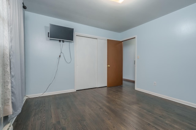 unfurnished bedroom with a closet, dark hardwood / wood-style flooring, and a baseboard radiator