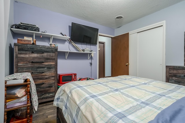 bedroom featuring dark hardwood / wood-style flooring, a textured ceiling, and a closet