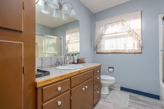 bathroom featuring backsplash, vanity, wood-type flooring, a chandelier, and toilet