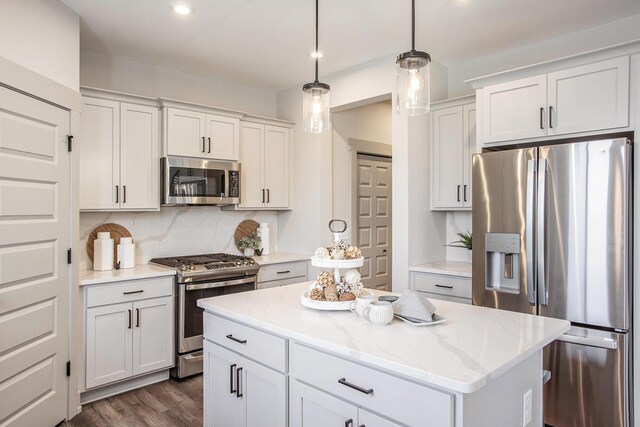 kitchen featuring backsplash, stainless steel appliances, pendant lighting, a center island, and dark wood-type flooring