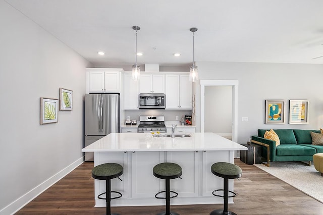 kitchen with decorative light fixtures, a center island with sink, a kitchen breakfast bar, and appliances with stainless steel finishes