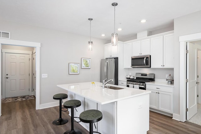 kitchen featuring white cabinetry, stainless steel appliances, a kitchen island with sink, and hanging light fixtures