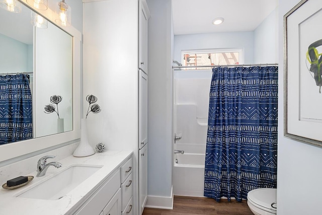 full bathroom featuring hardwood / wood-style flooring, shower / tub combo with curtain, vanity, and toilet