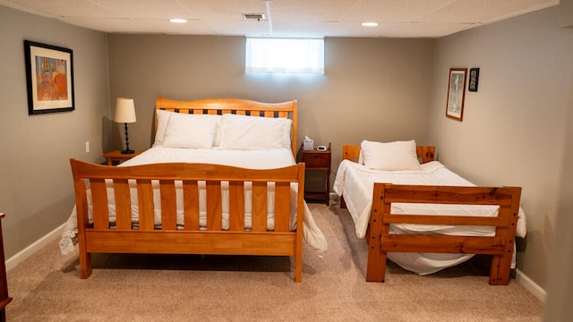 carpeted bedroom featuring a drop ceiling