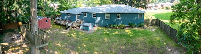 back of property with a wooden deck, a yard, and a storage shed