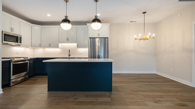 kitchen with decorative backsplash, appliances with stainless steel finishes, and pendant lighting