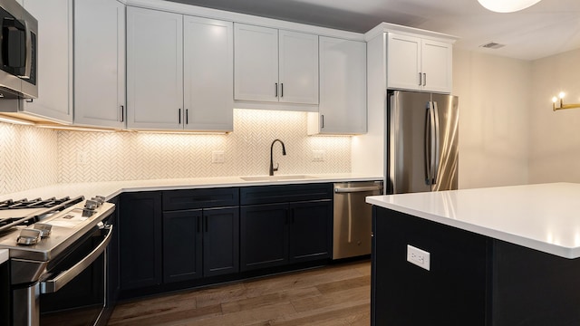 kitchen featuring visible vents, a sink, wood finished floors, appliances with stainless steel finishes, and light countertops